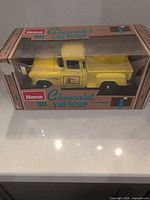 Full boxed model showing front and side of yellow truck inside packaging