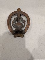 Full view of brass horseshoe door knocker showing overall design
