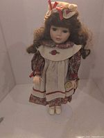 Full view of porcelain doll on stand showing dress, bonnet and overall condition