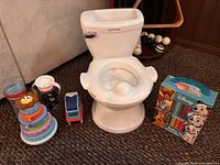 All items together showing potty, stacking toy, cups, toy vehicle, Disney book set