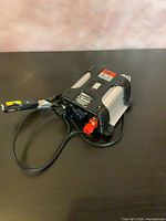 Top view showing Black & Decker branding, 200-watt spec label, red and black terminals, attached cable