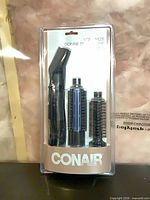 Front view of sealed Conair hot air styling brush package showing handle and three attachments