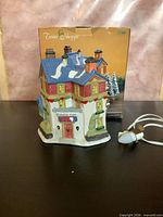 Front view of porcelain village house, box and light cord