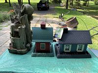 Overall view of three items: stump fountain decoration, red barn feeder, blue house feeder