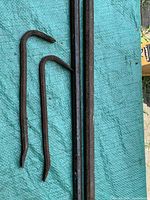 Top view of two smaller gooseneck pry bars beside two long hex crowbars on tarp