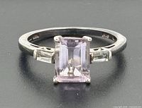 Top view of sterling silver ring with emerald-cut pink center stone and clear baguette accents