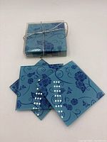 Stack of seven teal glass coasters tied together, three spread to show design