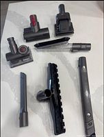All six Dyson vacuum attachments laid out on surface