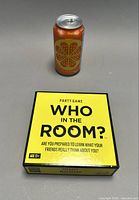 Front of boxed Who in the Room? game with soda can for scale