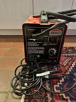 Front three-quarter view showing welder, MIG gun, ground clamp and cables