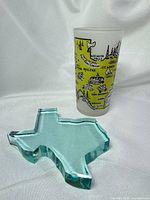Front view of aqua-teal Texas-shaped glass paperweight with reference object