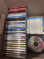 Boxed stack of 29 jewel-case audio CDs showing assorted titles and LaserMagic cleaning disc