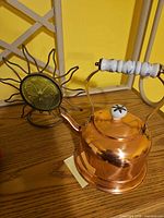 Copper teapot and sunburst candle holder side by side on table