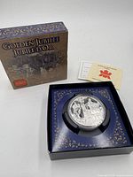 Outer retail box and opened presentation case displaying encapsulated coin with certificate behind