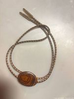 Front view of bolo tie showing wood slide and braided leather cords