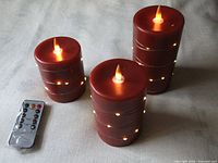 Three red wax flameless LED candles lit with remote control shown