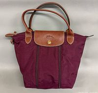 Front view of plum nylon Longchamp tote with leather handles and flap