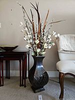 Full view of bronze ceramic floor vase with artificial floral stems