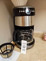 Front view of KitchenAid coffee maker with carafe, reusable filter basket and manual visible