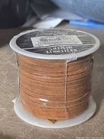 Front view of sealed brown leather lace spool on plastic core