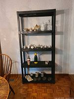 Full view of four black plastic shelves holding assorted decorative and barware items