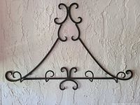 Front view of black wrought iron wall rack showing scroll design and five hooks