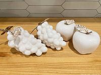 Full set: two apple and two grape figurines on wooden surface