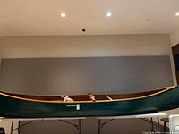 Full starboard side view of green cedar strip canoe on stand