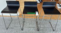 Front view of three black IKEA Sebastian bar stools on rug