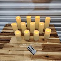 Twelve illuminated ivory LED candles arranged on tabletop with remote in foreground