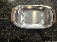 Top view of stainless steel dish showing teak handles