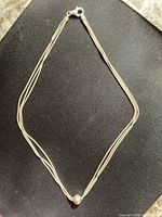 Full view of three-strand snake chain necklace laid flat
