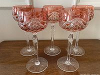 Front view of all five red cut-to-clear crystal wine glasses standing on table