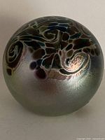 Full view of iridescent glass paperweight showing swirl design