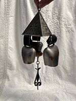 Front view of metal wind chime showing three bells, triangular cap, hanging loop and clapper