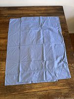 Two blue standard pillowcases laid flat on wooden surface
