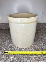 Front view of cream stoneware crock with tape for scale