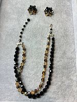 Full view of necklace and earrings on gray background