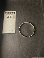 Full view of sterling silver rope bangle beside scale card