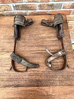 Full view of both climbing spurs laid flat showing complete straps and spikes