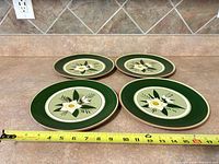 Four Stangl salad plates on countertop with tape measure showing diameter