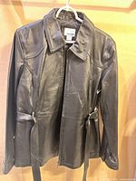 Front view of black leather jacket on hanger
