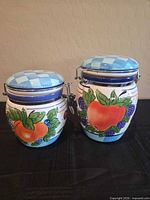 front view showing both ceramic canisters with fruit design and checkered lids