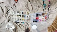 Both organizer boxes open showing beads, feather charms and necklaces