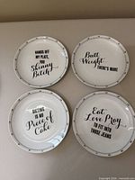 All four dessert plates laid out showing humorous phrases and rim design