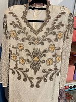 Front view of full-length ivory silk beaded gown on hanger