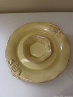 Top view of yellow ceramic platter with integrated bowl showing overall design and grape motif