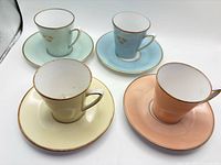 Four pastel porcelain cup and saucer sets displayed upright