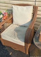 Front view of brown wicker swivel chair with beige cushions