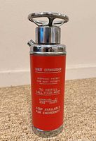 Front view showing red body, white "Thirst Extinguisher" text and chrome pump top